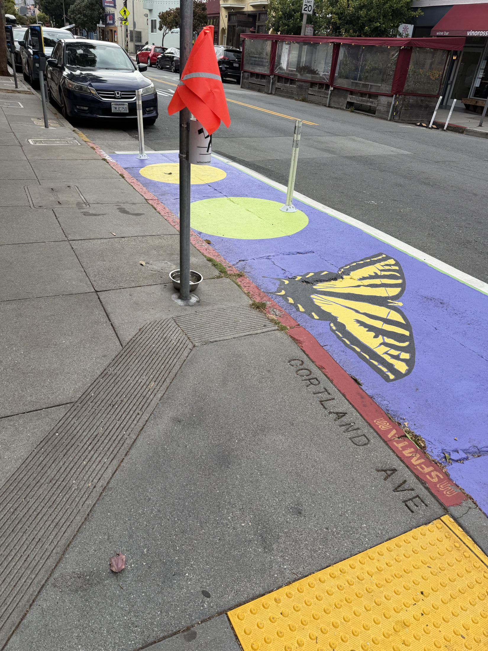 A colorful butterfly mural in a protected daylighting zone on Cortland Avenue